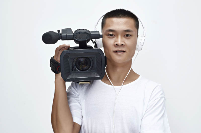 白色背景下手持摄像机进行录制拍摄的摄像师