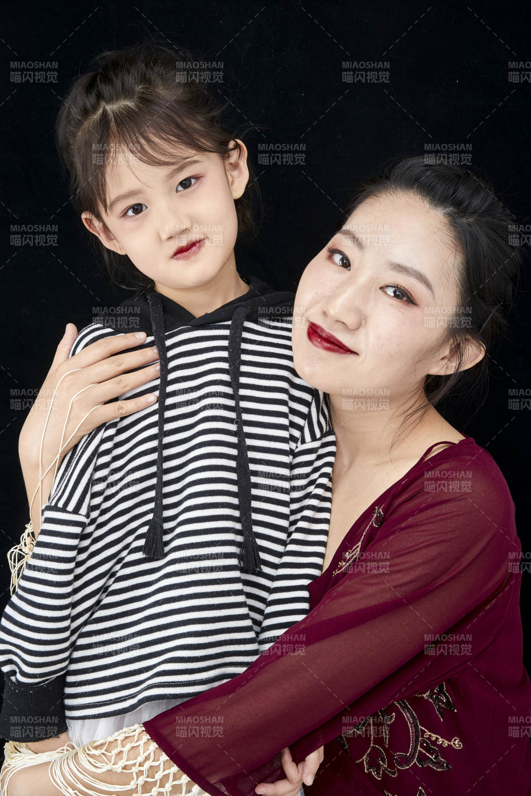 黑色背景的美麗媽媽與可愛女兒親子人像