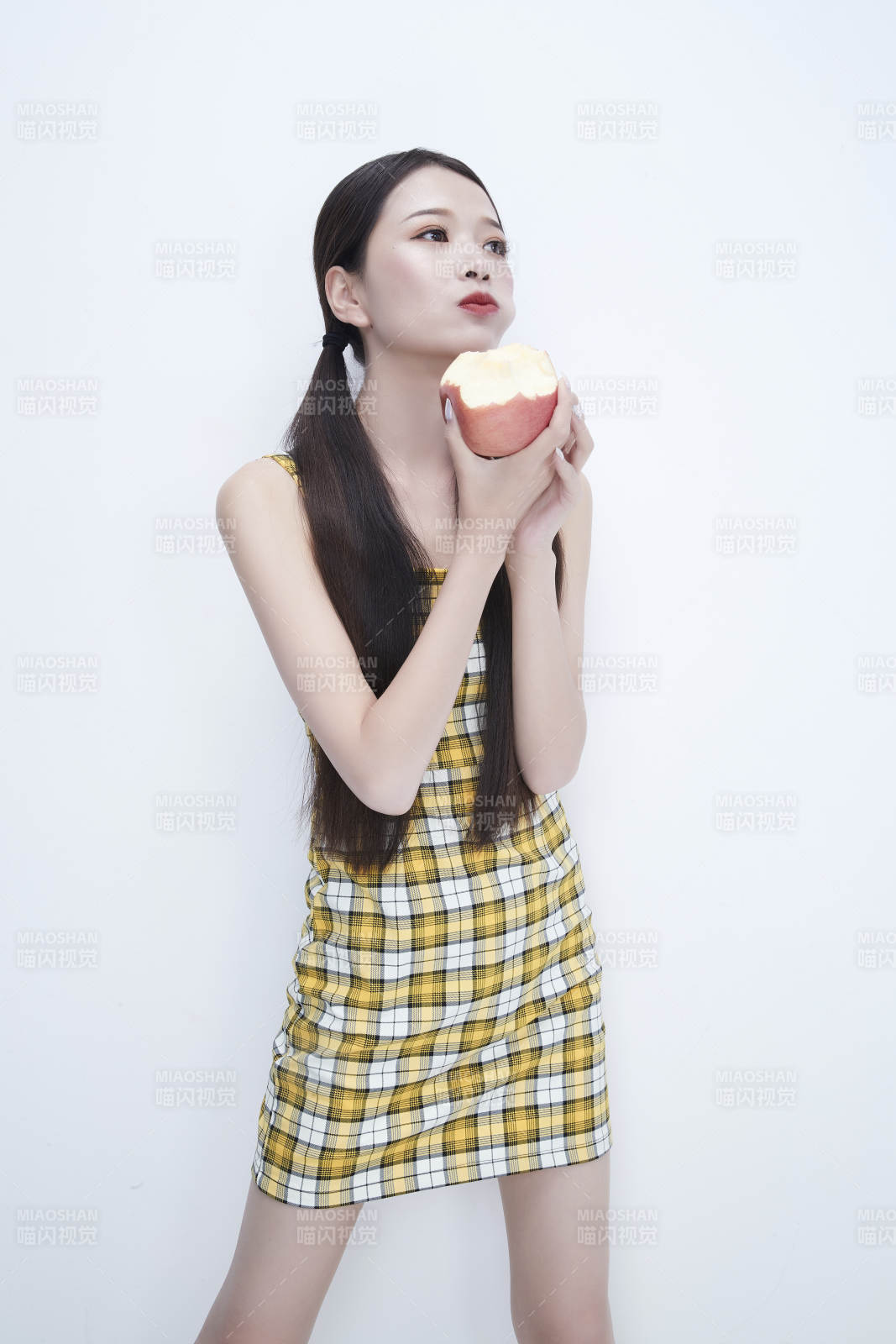 手拿蘋果身穿格子吊帶裙的亞洲可愛少女人像