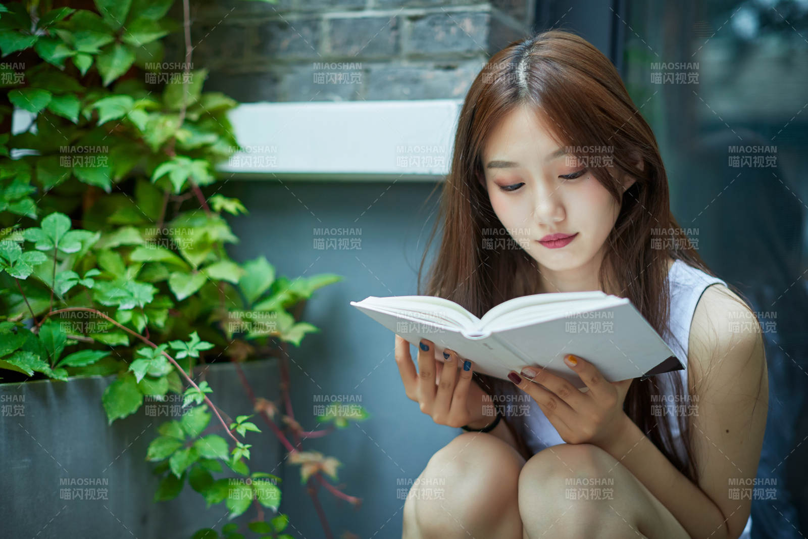 院子里坐在長椅上閱讀書籍的亞洲長發少女