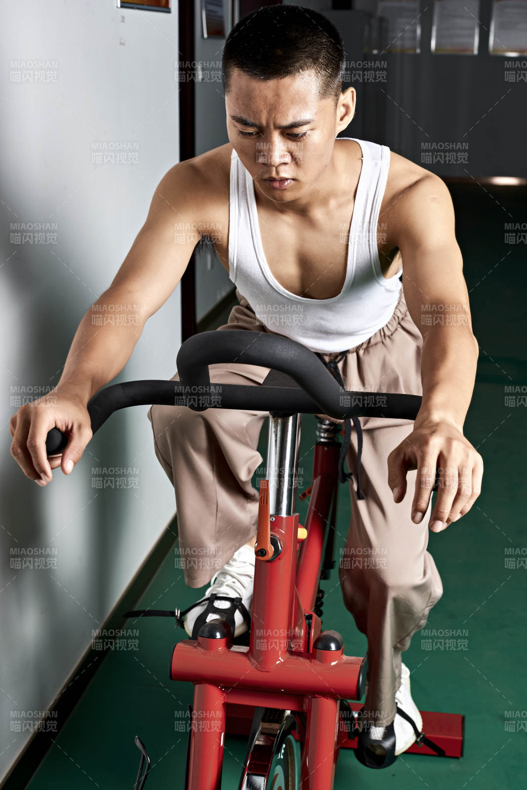 在室內(nèi)進(jìn)行動感單車鍛煉的亞洲健身男士形象