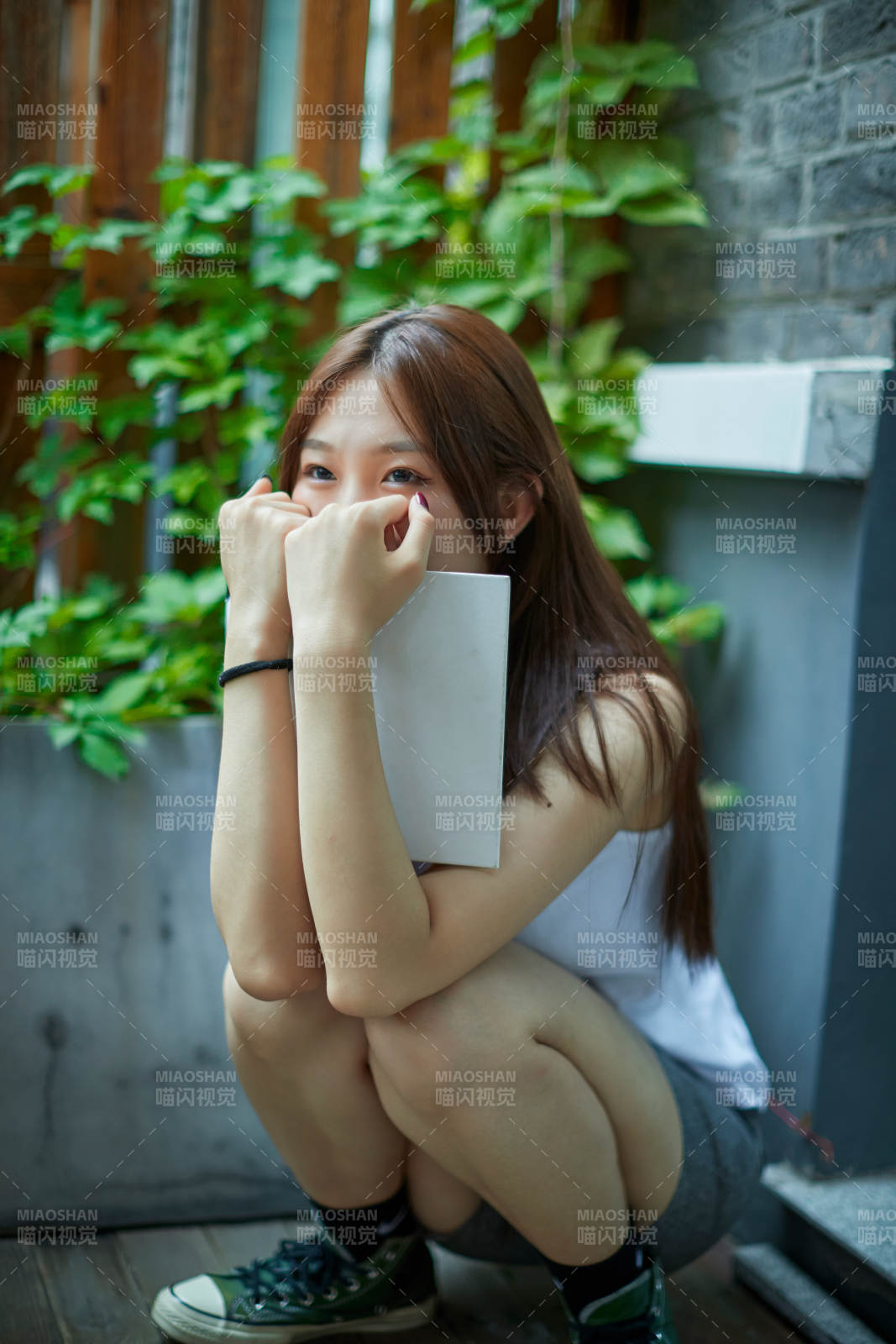 院子里坐在长椅上阅读书籍的亚洲长发少女