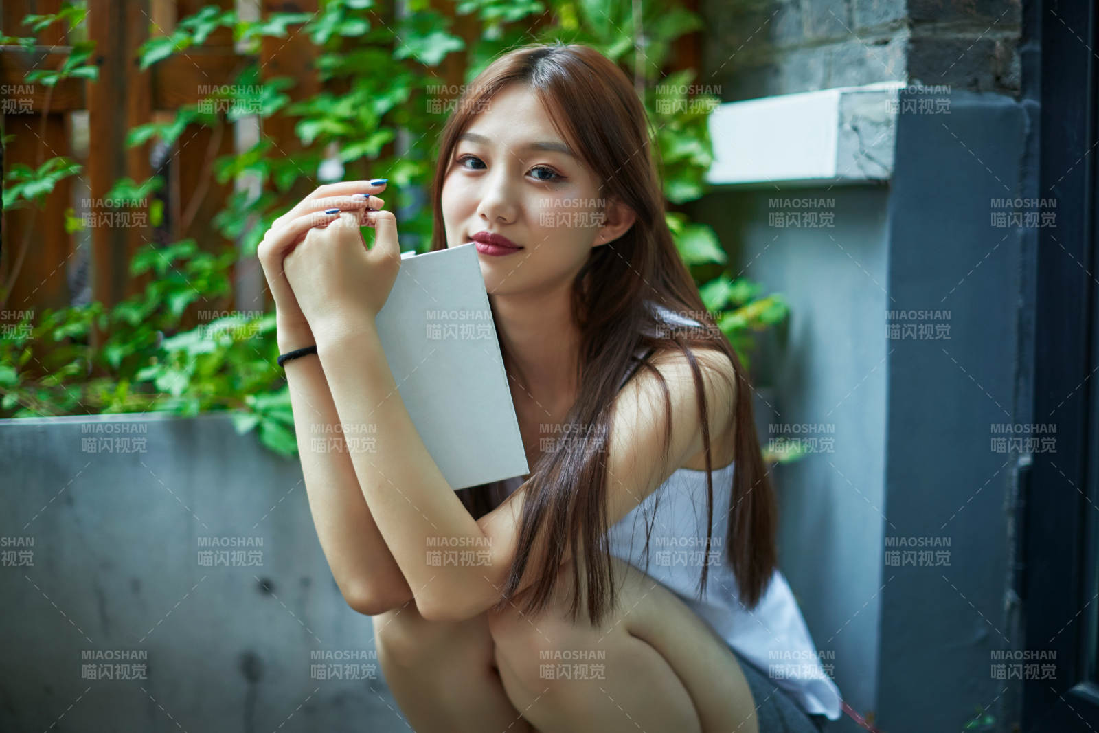 院子里坐在長椅上閱讀書籍的亞洲長發少女