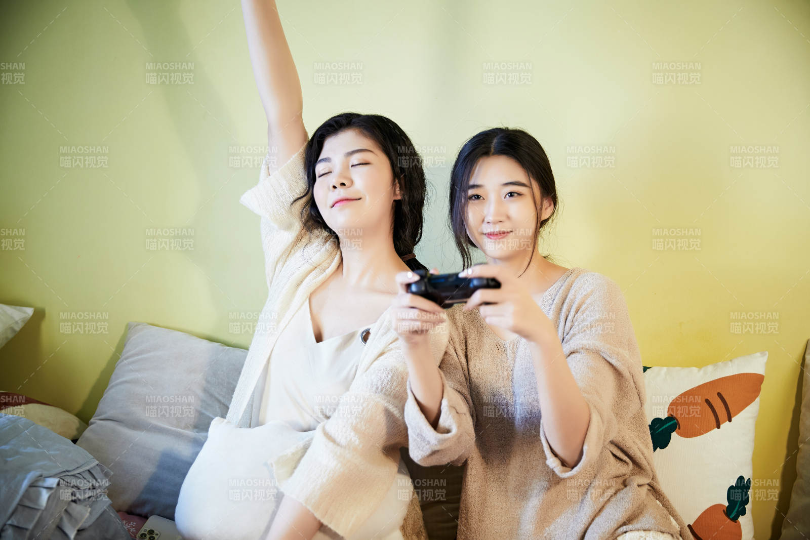 坐在床上打電玩的倆位美女