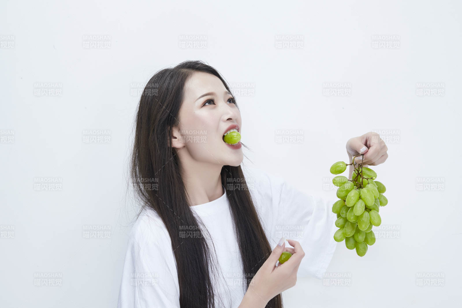 吃葡萄的穿白色长T血衫的长发可爱少女人像
