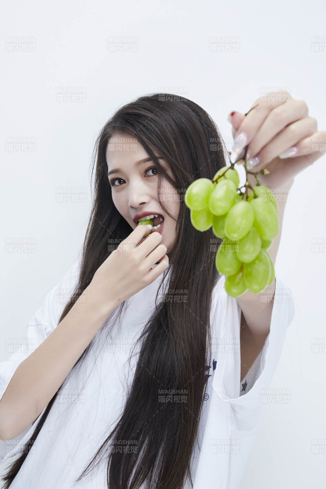 吃葡萄的穿白色长T血衫的长发可爱少女人像