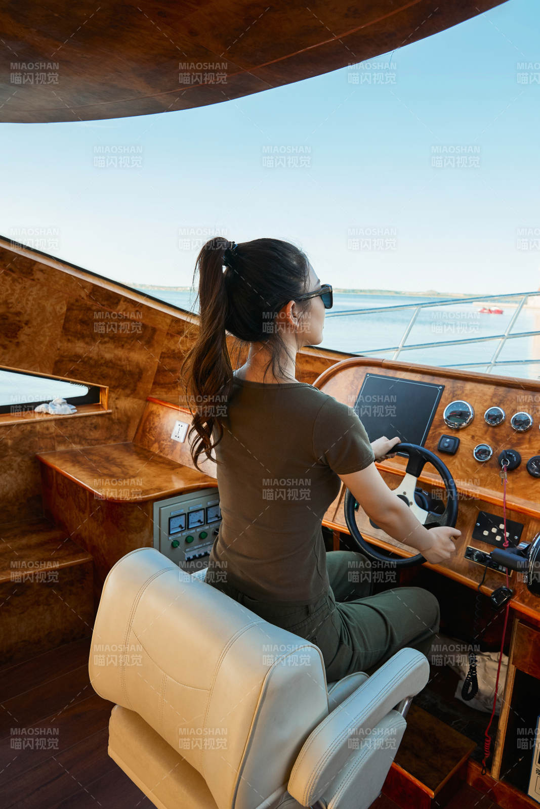 在海上戴着墨镜驾驶游艇的亚洲少女