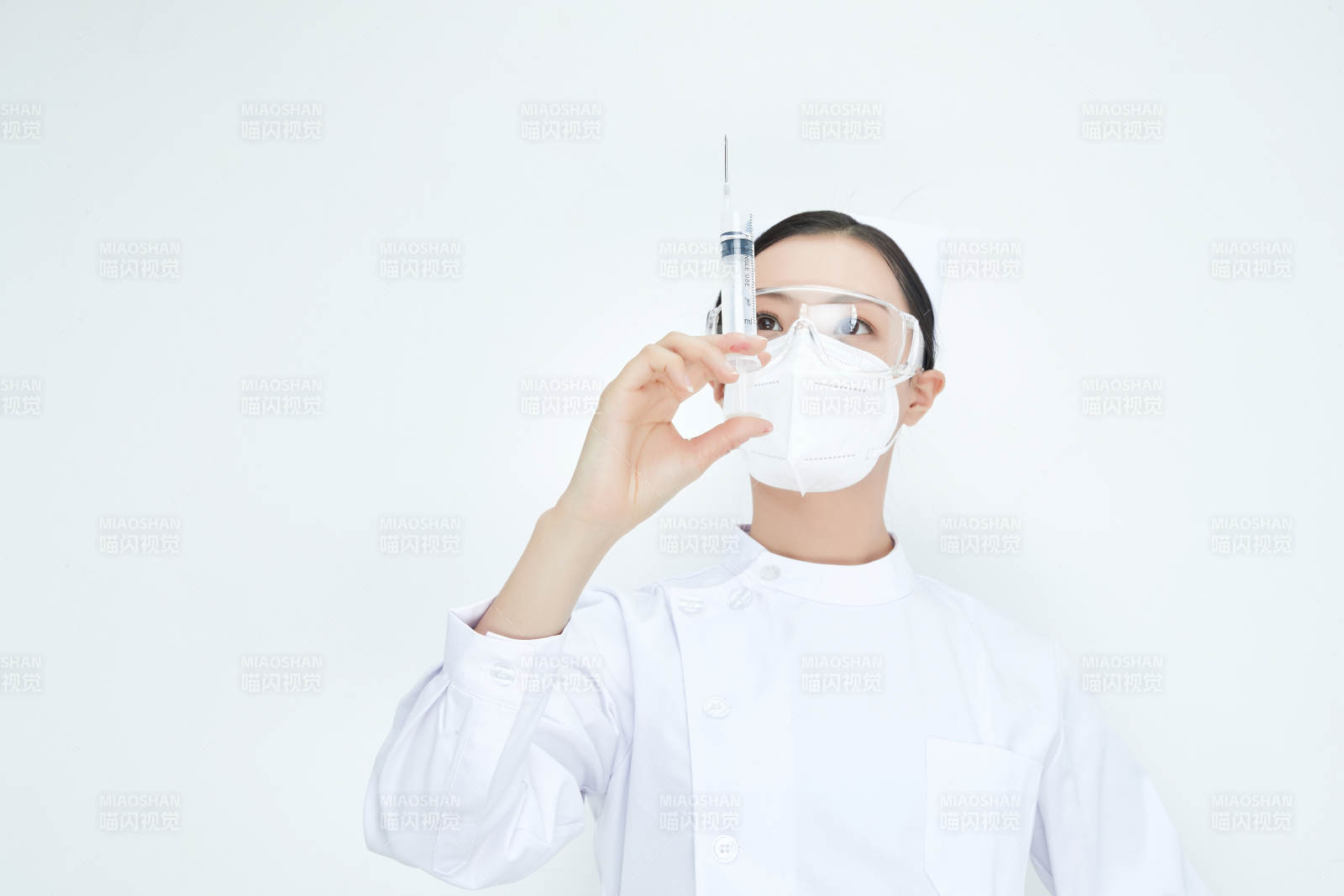 穿护士服戴口罩手执针筒的年轻女护士