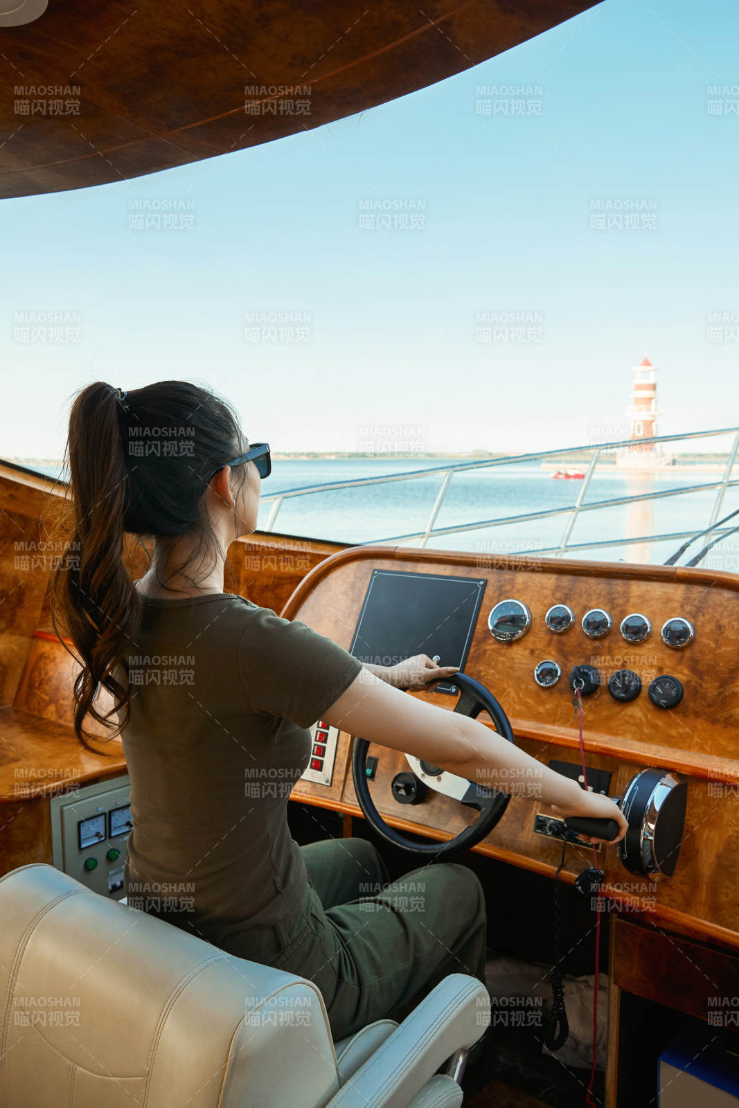 在海上戴着墨镜驾驶游艇的亚洲少女