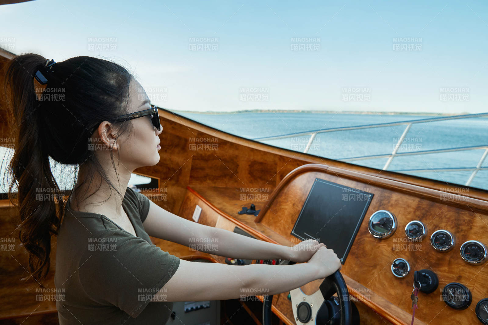 在海上戴著墨鏡駕駛游艇的亞洲少女