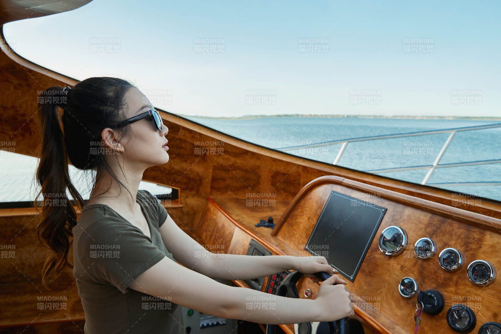 在海上戴着墨镜驾驶游艇的亚洲少女