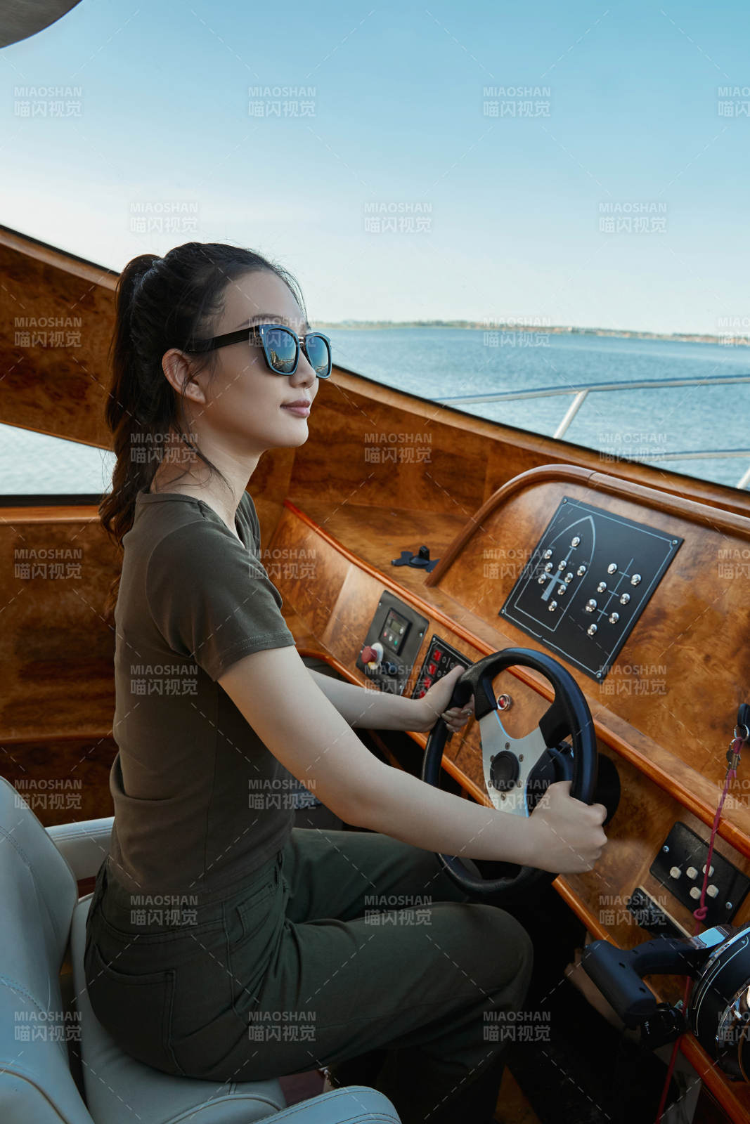 在海上戴着墨镜驾驶游艇的亚洲少女
