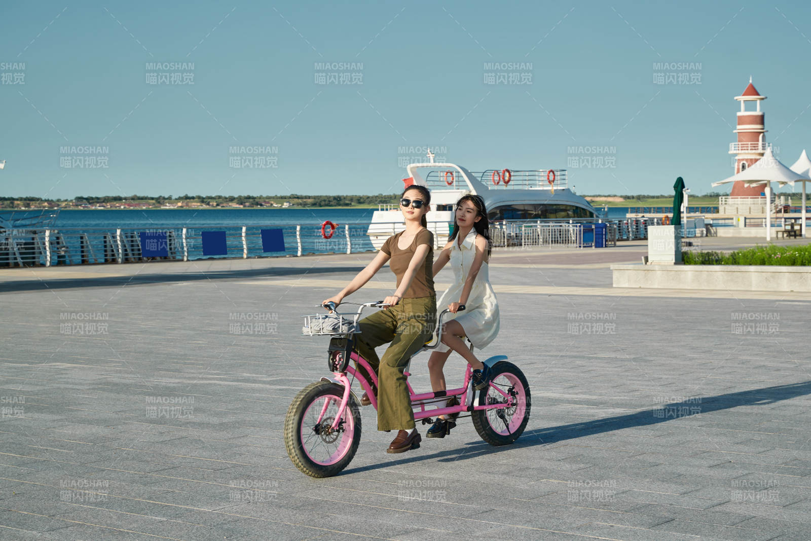 夕阳下湖边码头骑双人脚踏车的闺蜜少女