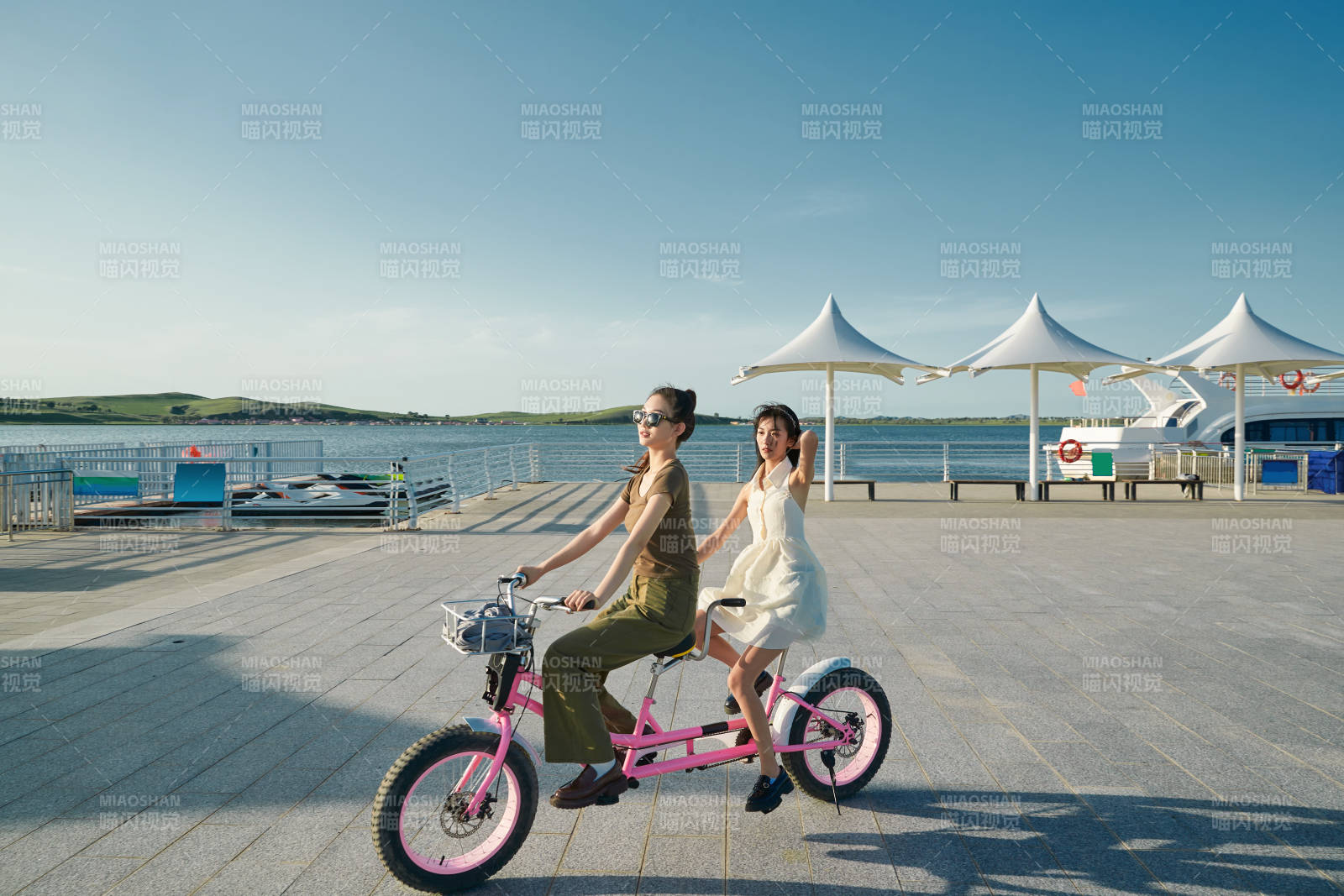 夕陽下湖邊碼頭騎雙人腳踏車的閨蜜少女