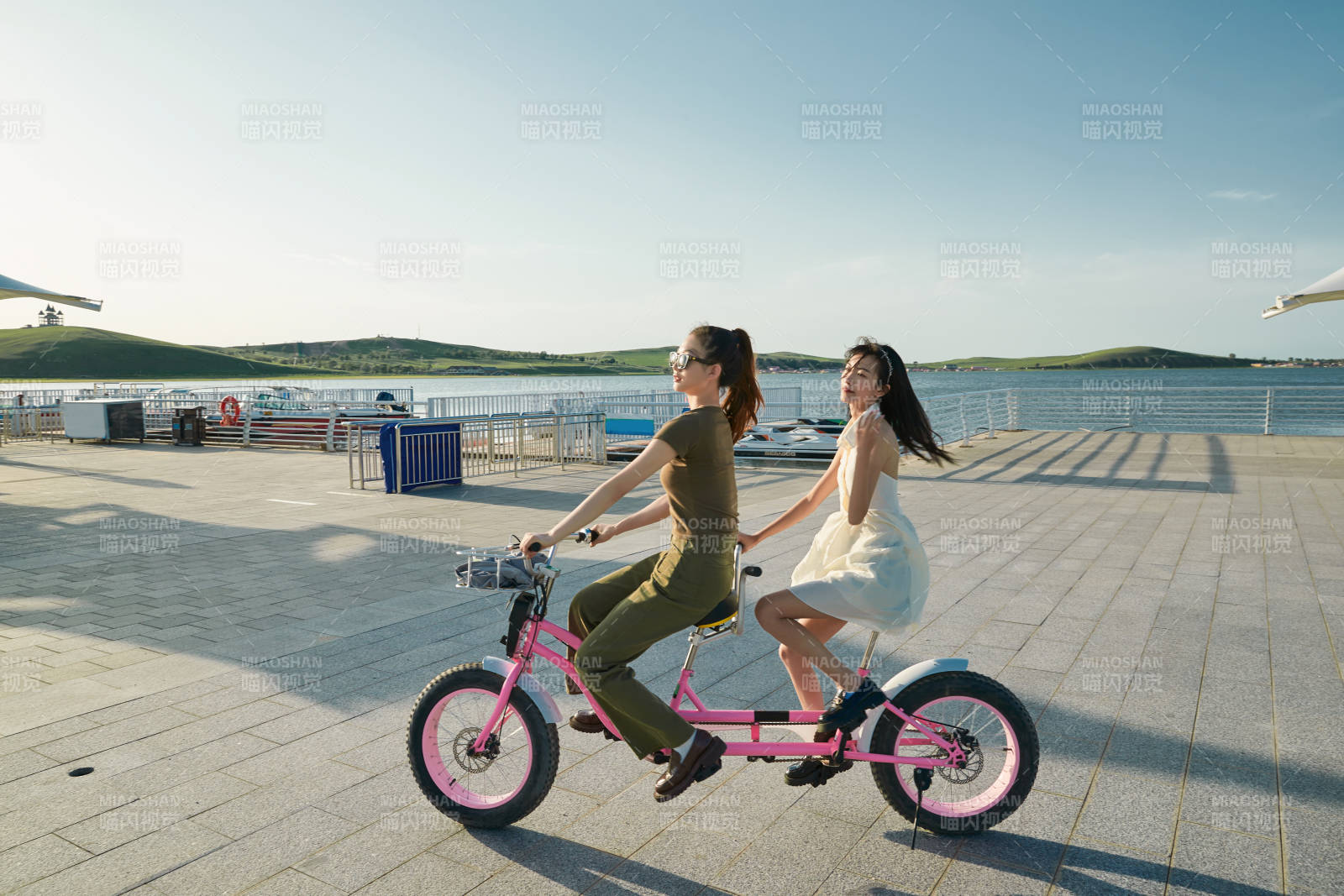 夕陽下湖邊碼頭騎雙人腳踏車的閨蜜少女