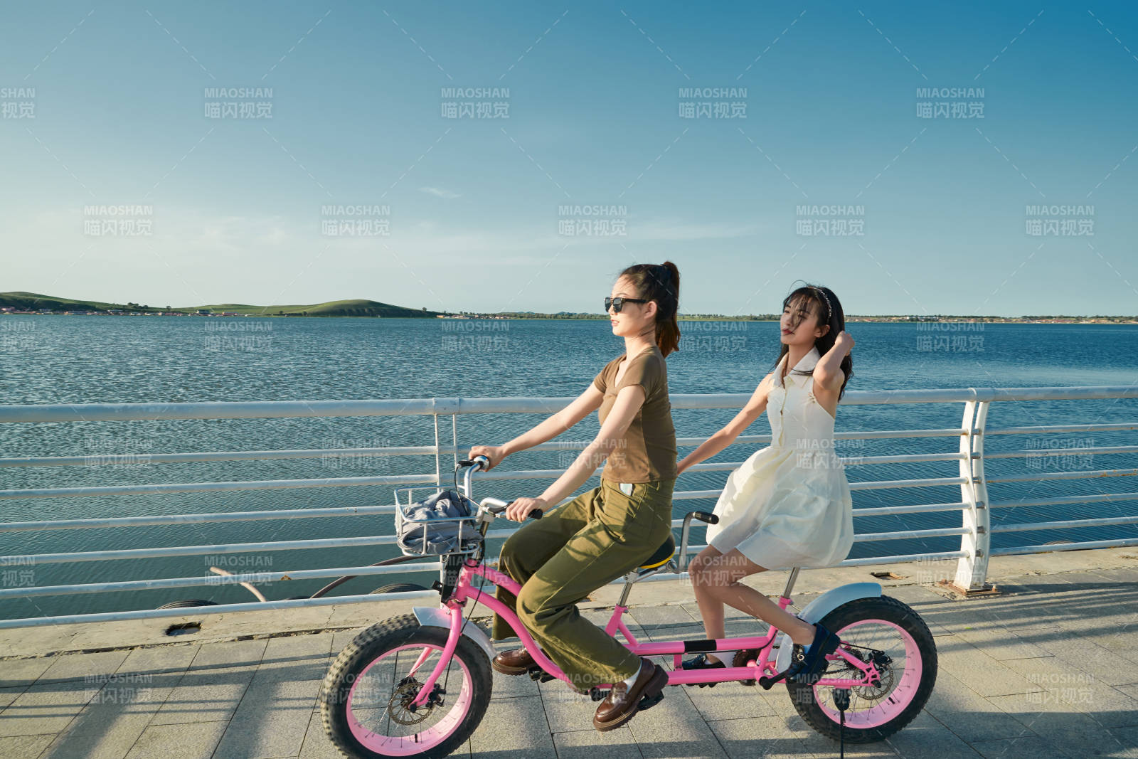 夕陽下湖邊碼頭騎雙人腳踏車的閨蜜少女
