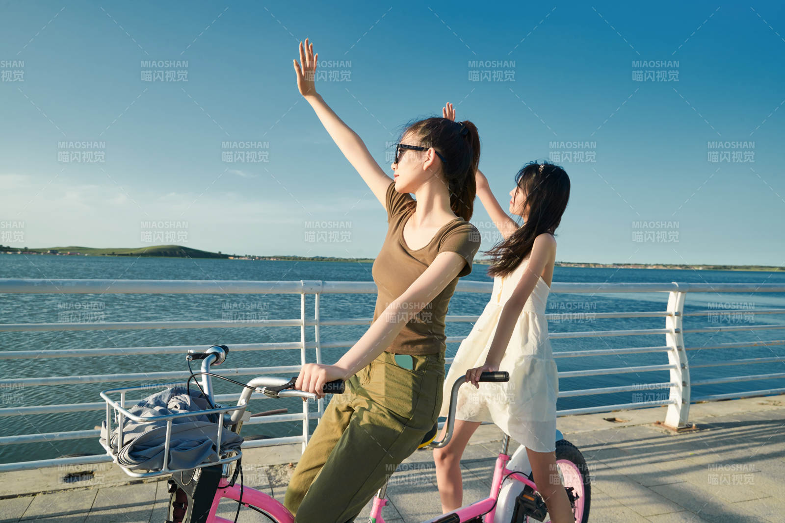 夕陽下湖邊碼頭騎雙人腳踏車的閨蜜少女