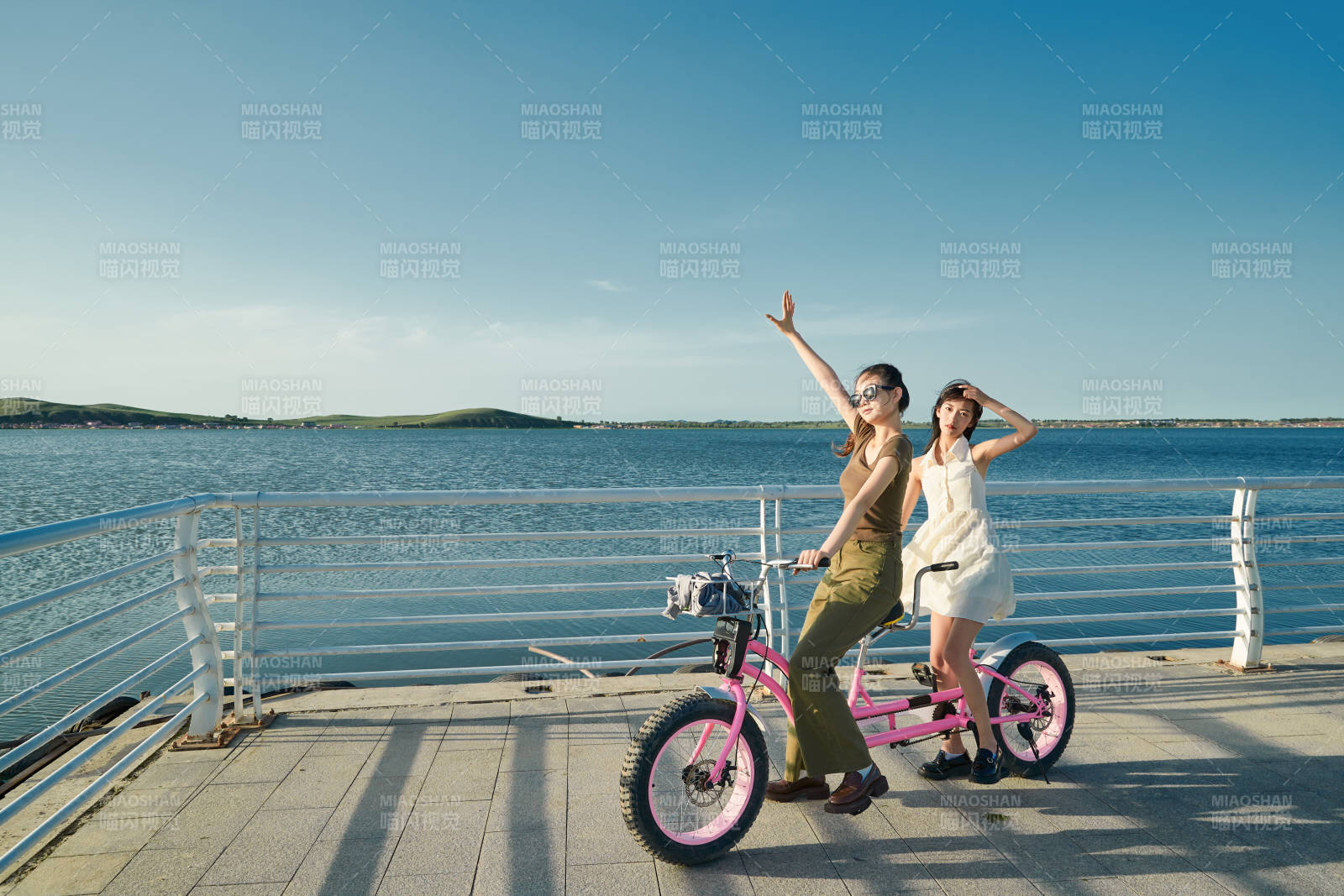 夕阳下湖边码头骑双人脚踏车的闺蜜少女