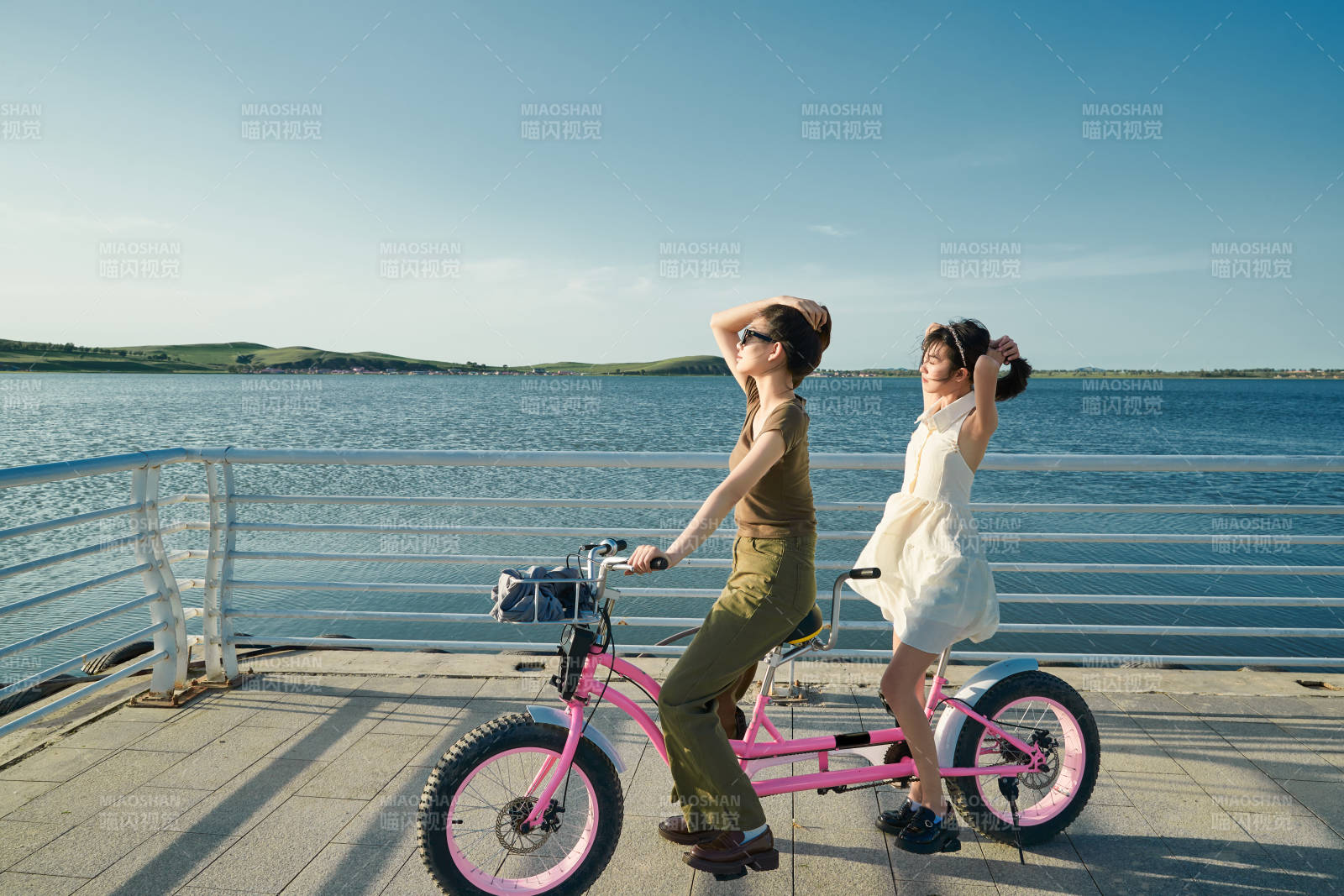 夕陽下湖邊碼頭騎雙人腳踏車的閨蜜少女