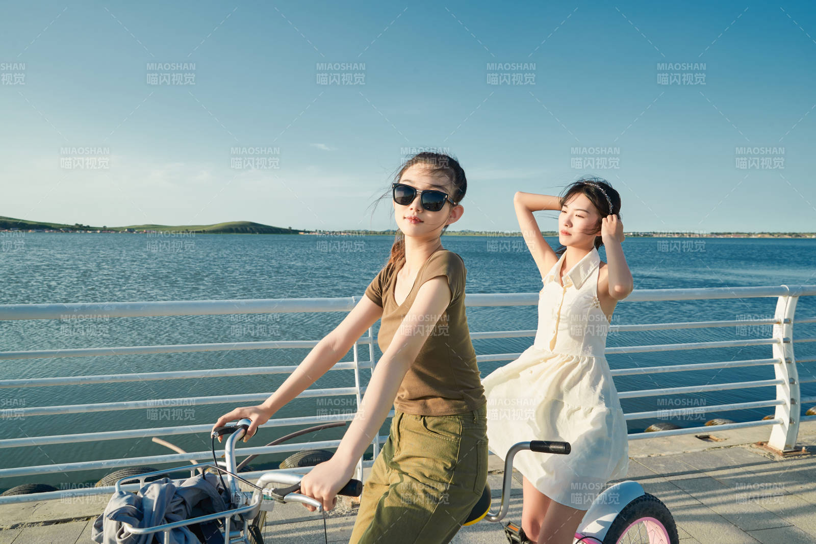 夕陽下湖邊碼頭騎雙人腳踏車的閨蜜少女