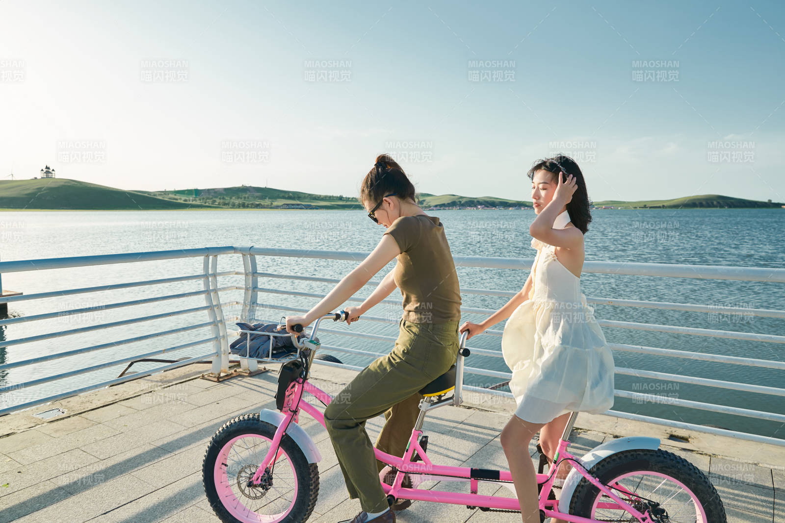 夕陽下湖邊碼頭騎雙人腳踏車的閨蜜少女