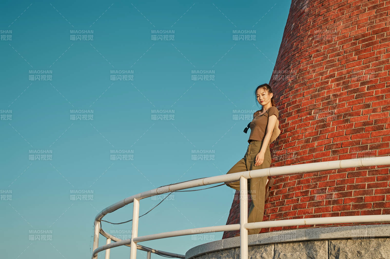 盛夏夕陽晚霞湖邊碼頭燈塔上的少女