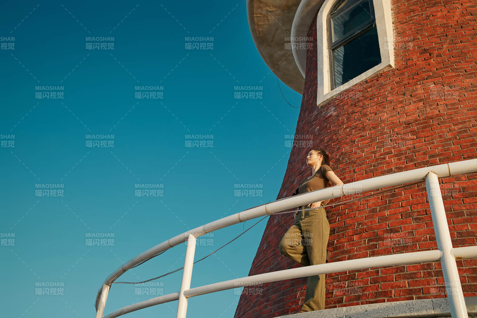 盛夏夕陽晚霞湖邊碼頭燈塔上的少女