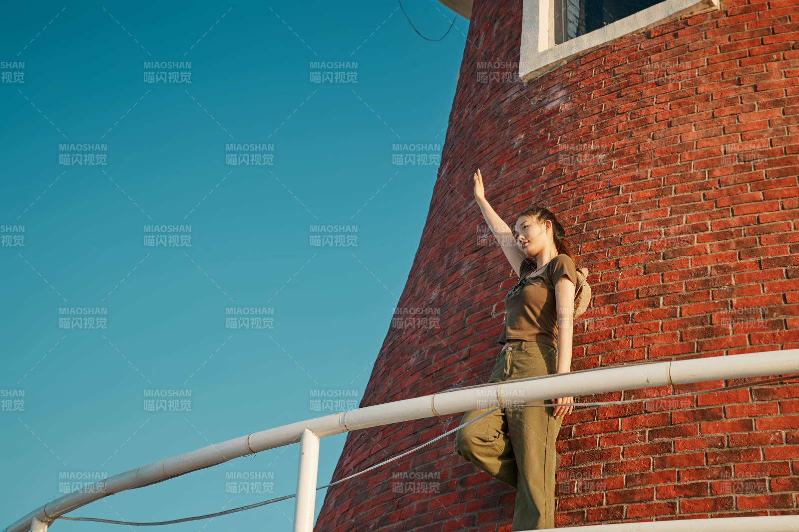 盛夏夕陽晚霞湖邊碼頭燈塔上的少女
