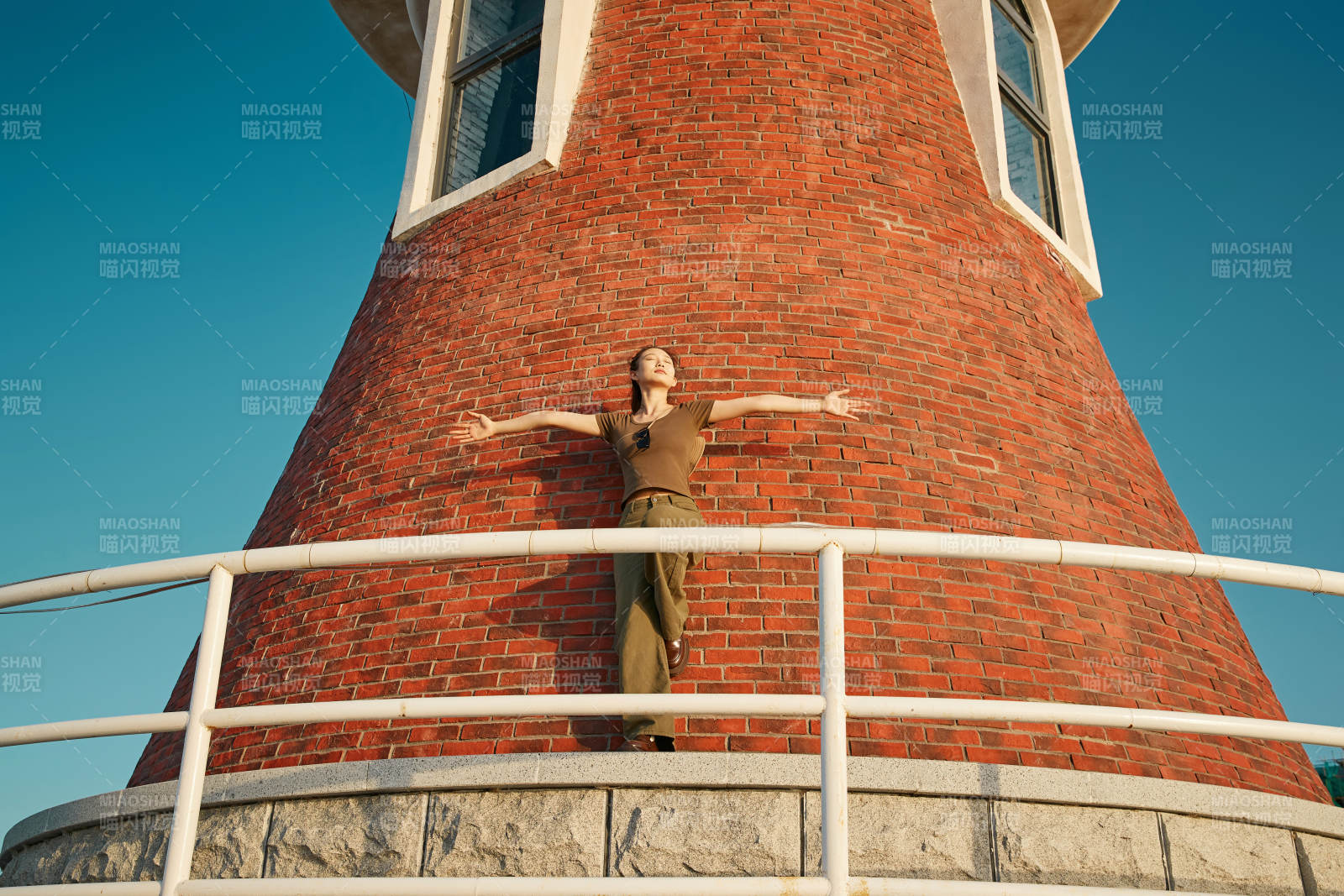 盛夏夕陽晚霞湖邊碼頭燈塔上的少女