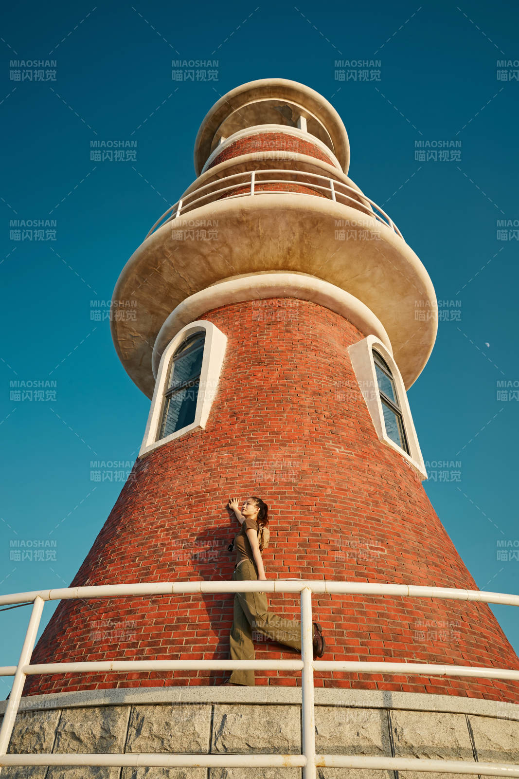 盛夏夕阳晚霞湖边码头灯塔上的少女