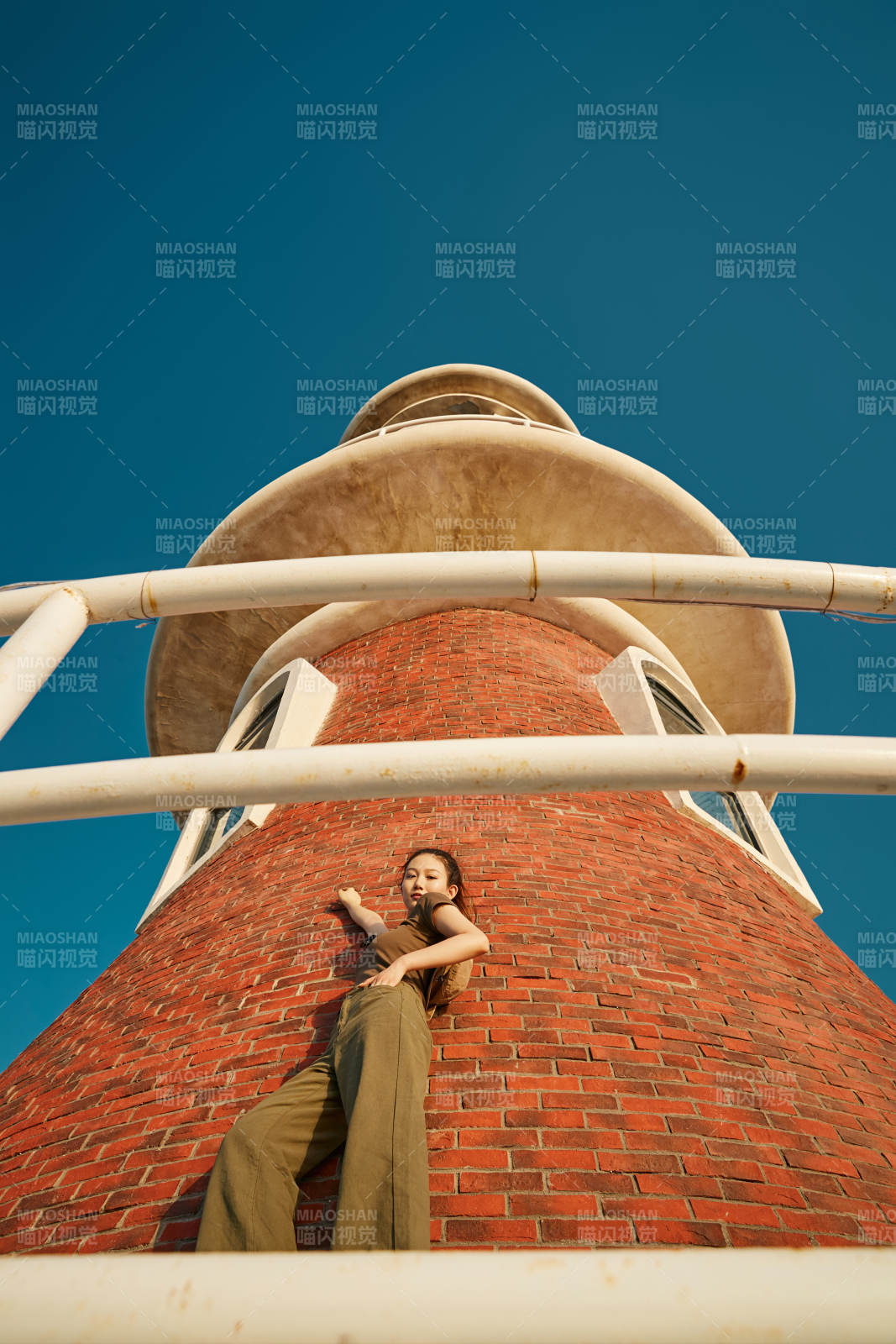 盛夏夕陽晚霞湖邊碼頭燈塔上的少女