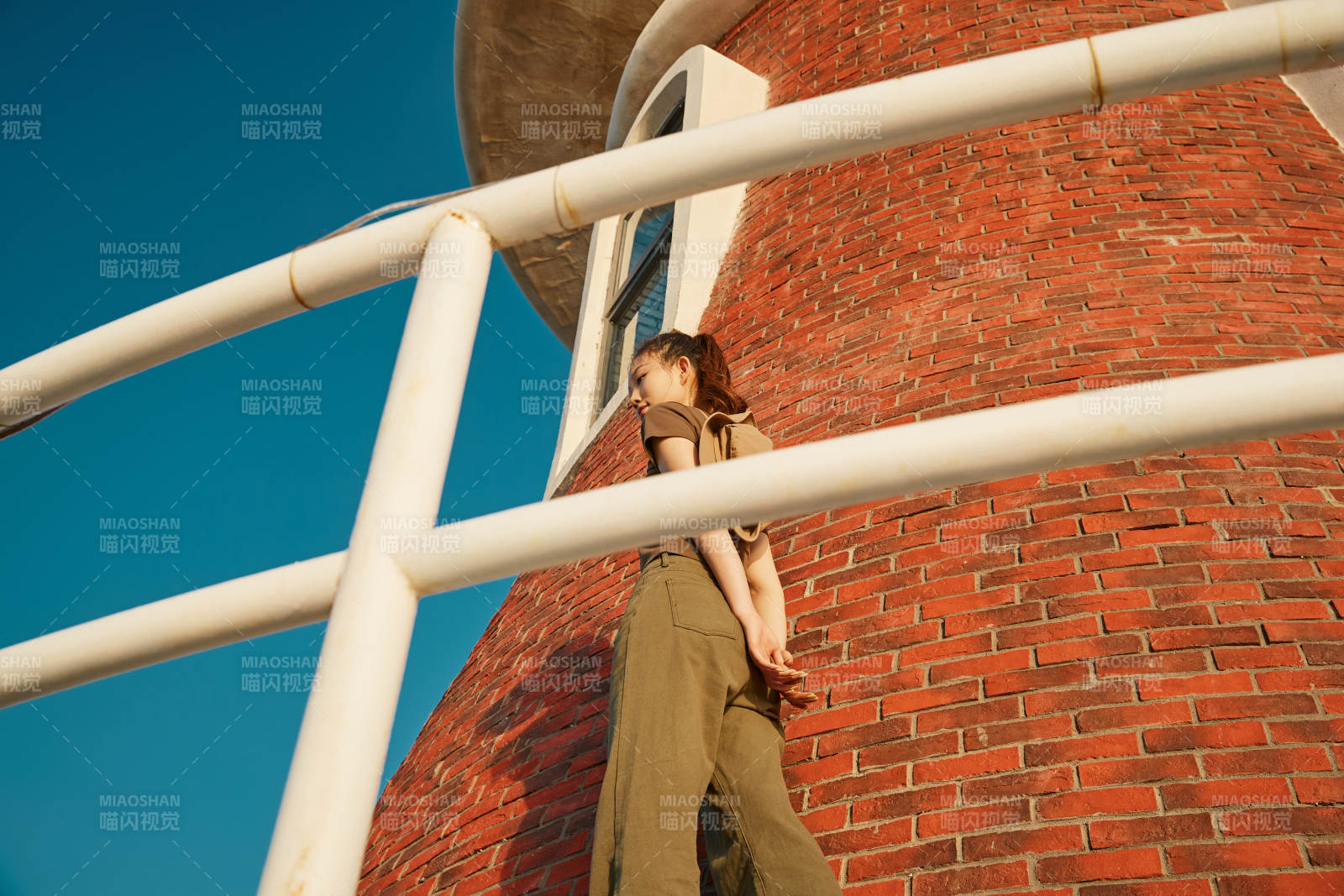 盛夏夕陽晚霞湖邊碼頭燈塔上的少女