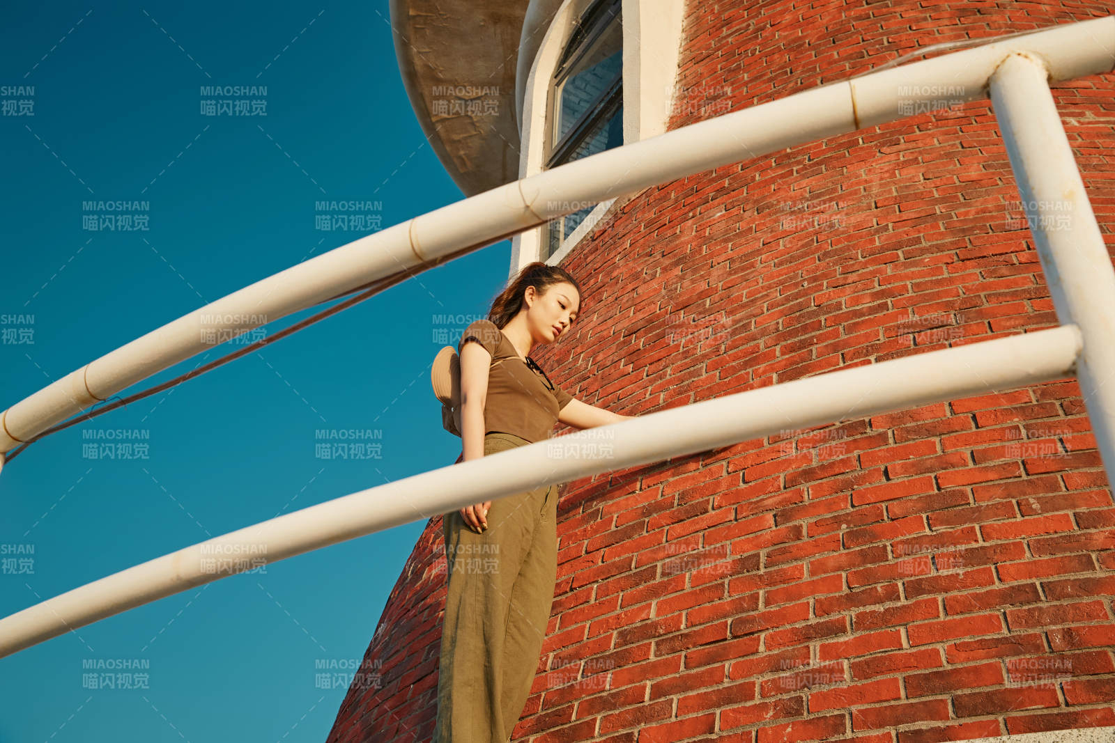 盛夏夕阳晚霞湖边码头灯塔上的少女