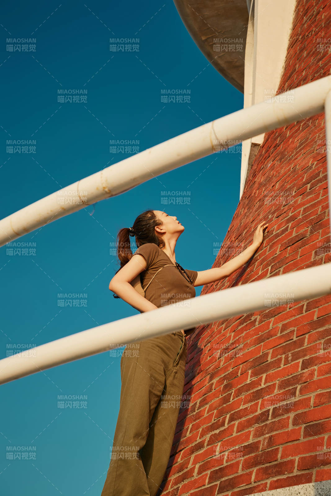 盛夏夕阳晚霞湖边码头灯塔上的少女