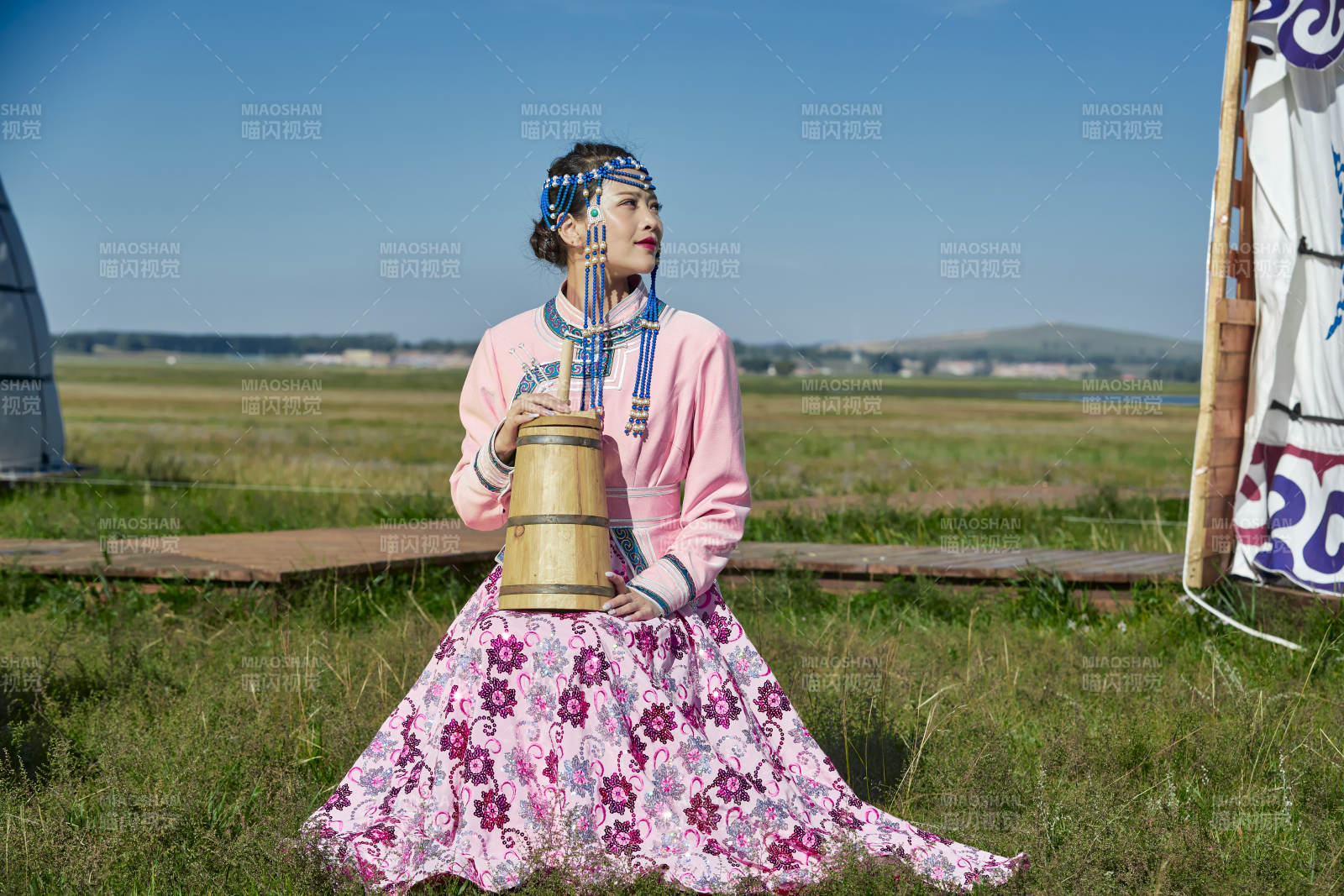 蒙古包前穿蒙古族飾懷抱奶茶桶的蒙族少女