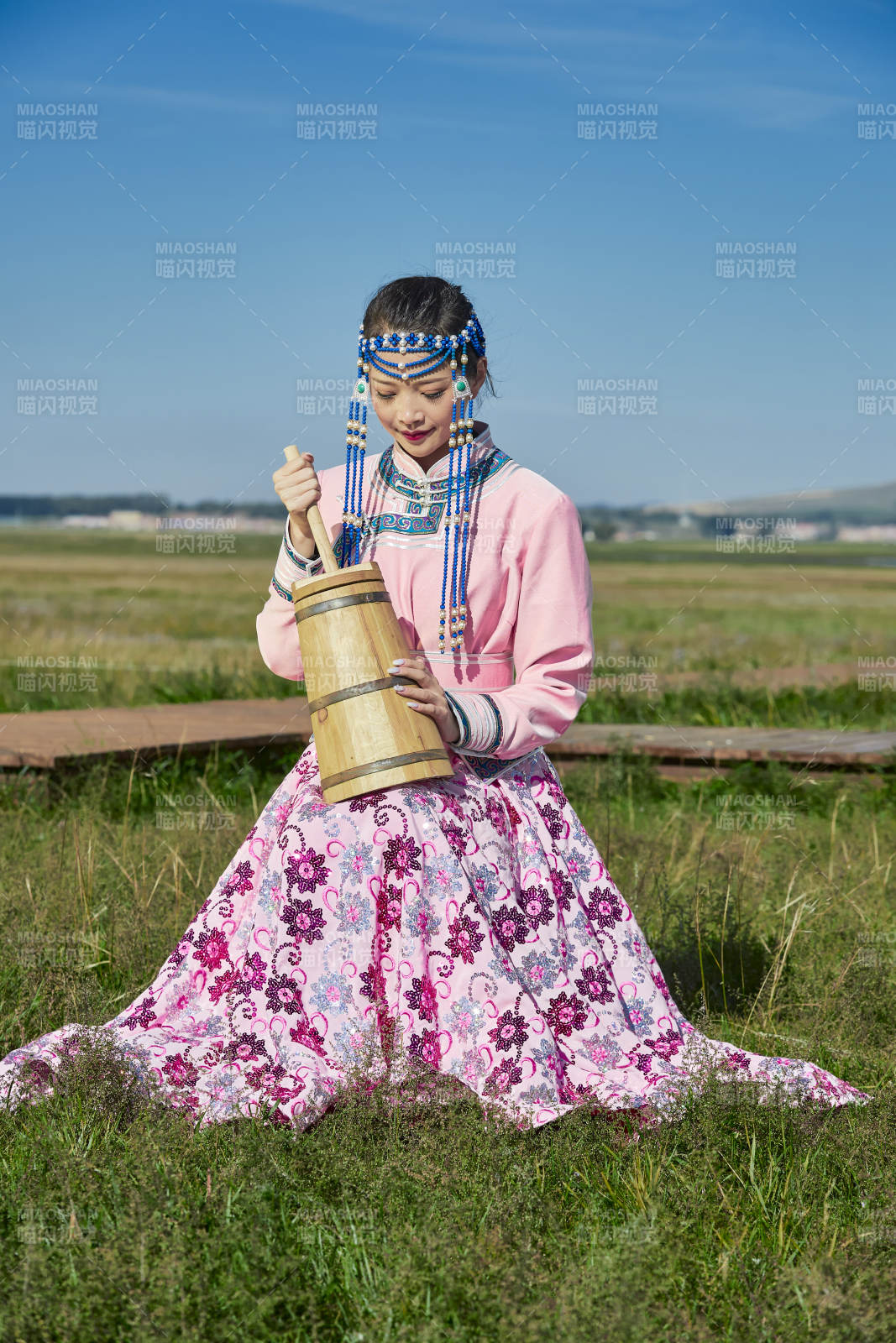 蒙古包前穿蒙古族飾懷抱奶茶桶的蒙族少女