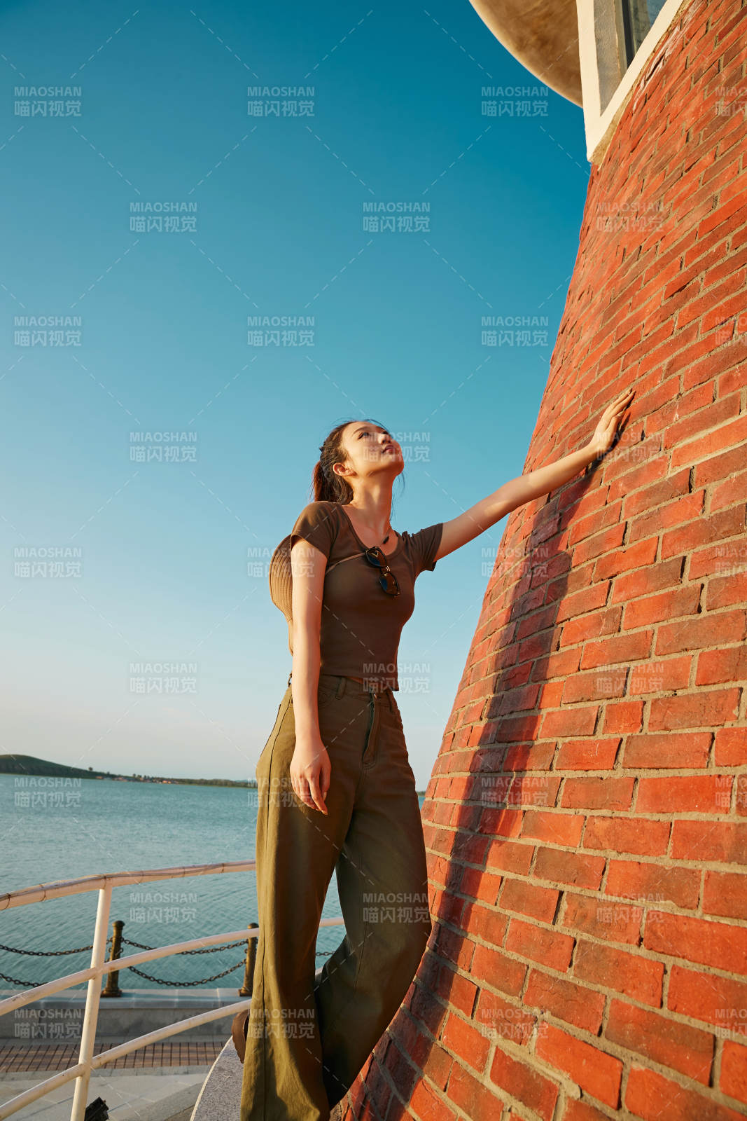 盛夏夕陽晚霞湖邊碼頭燈塔上的少女