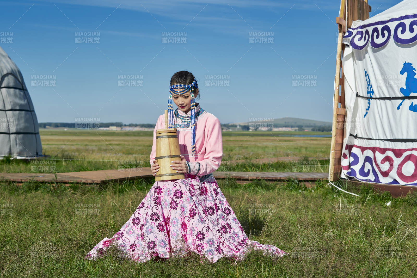 蒙古包前穿蒙古族饰怀抱奶茶桶的蒙族少女