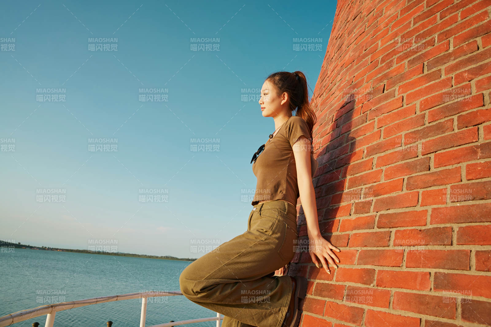 盛夏夕陽晚霞湖邊碼頭燈塔上的少女