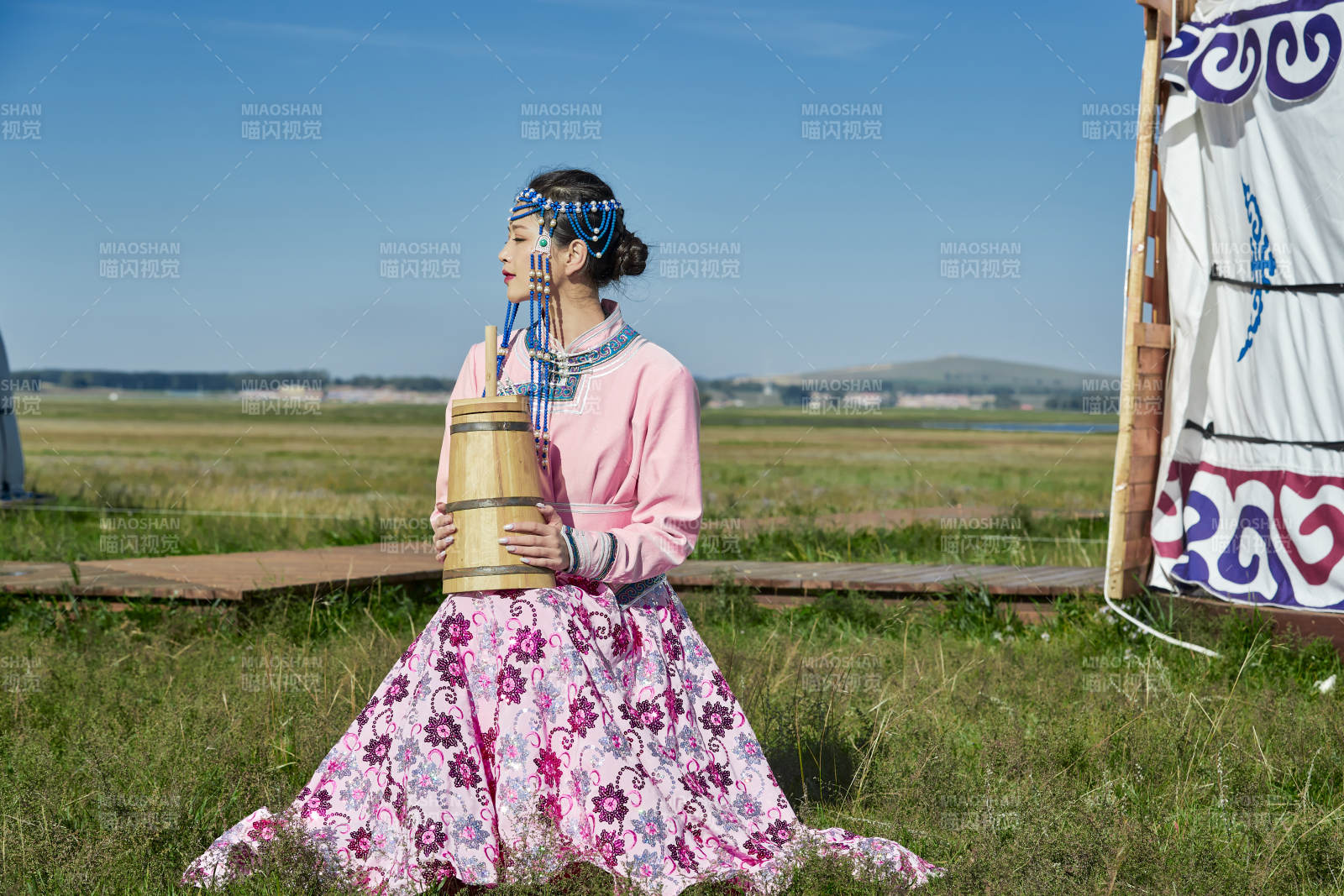 蒙古包前穿蒙古族飾懷抱奶茶桶的蒙族少女