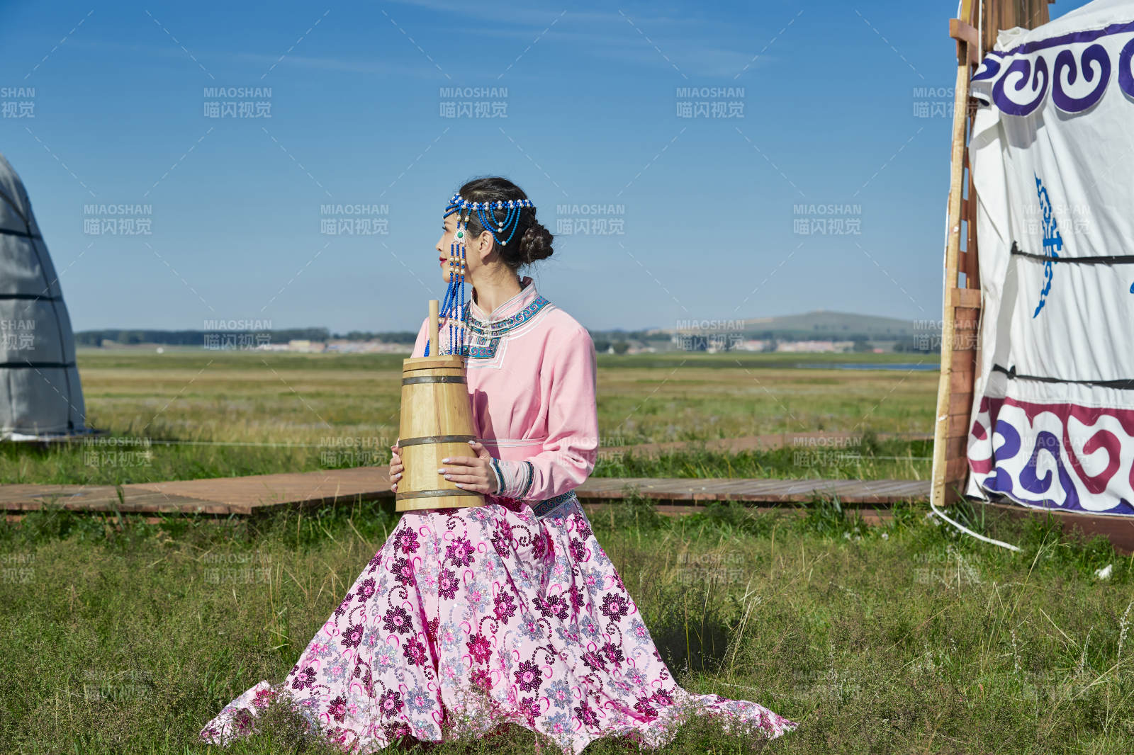 蒙古包前穿蒙古族飾懷抱奶茶桶的蒙族少女