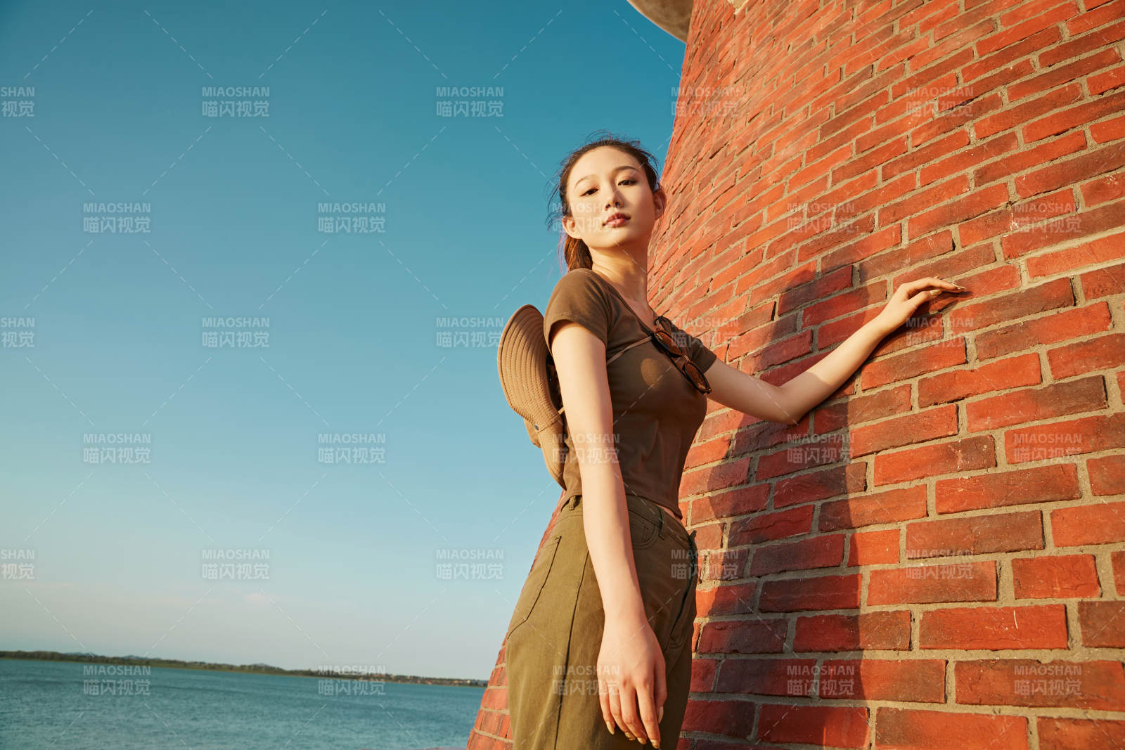 盛夏夕阳晚霞湖边码头灯塔上的少女