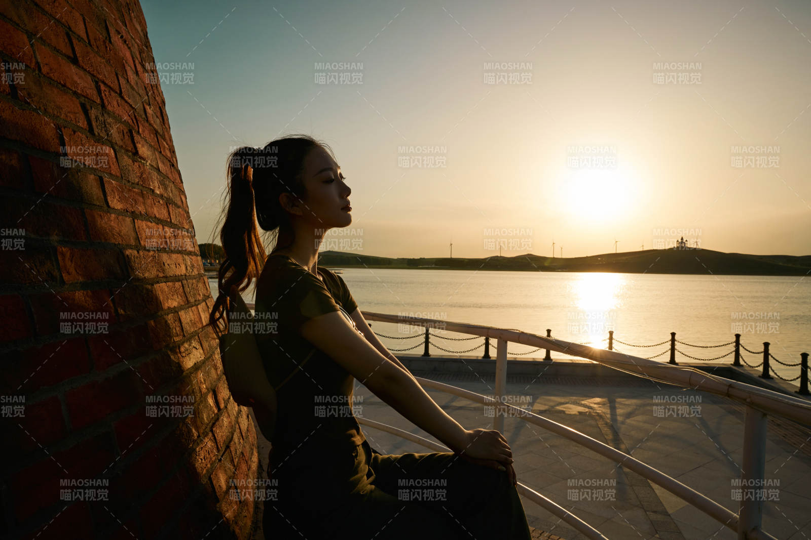 盛夏夕阳晚霞湖边码头灯塔上的少女