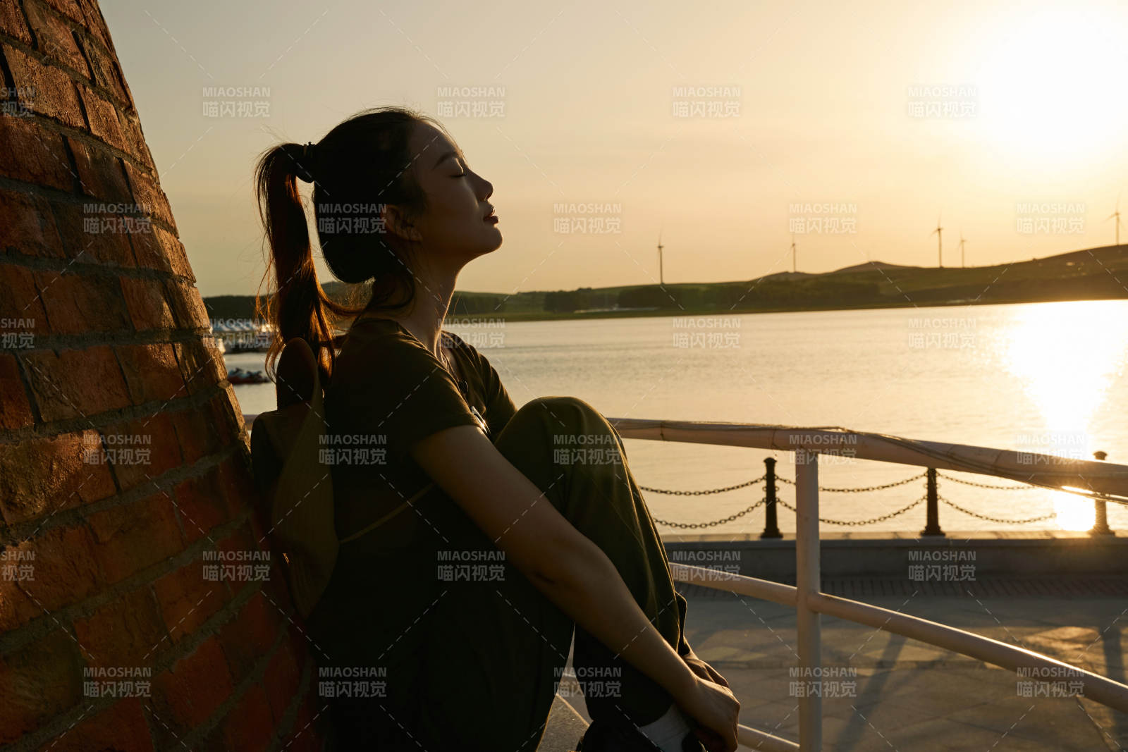 盛夏夕阳晚霞湖边码头灯塔上的少女