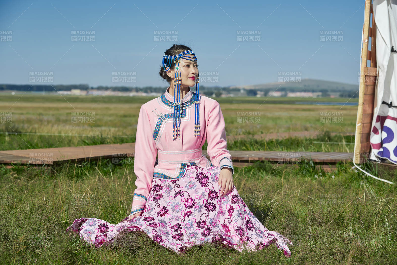 蒙古包前穿蒙古族飾懷抱奶茶桶的蒙族少女