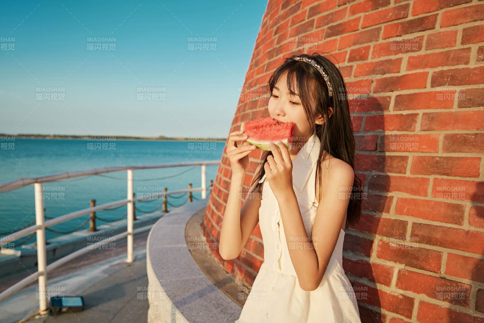 盛夏夕阳湖边码头灯塔上吃西瓜的少女图片
