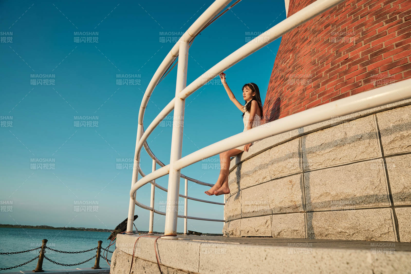 盛夏夕阳湖边码头灯塔上吃西瓜的少女