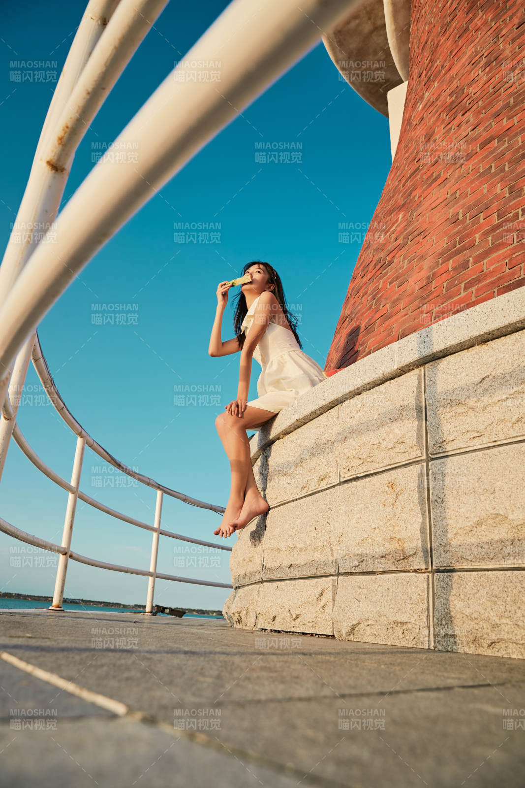 盛夏夕阳湖边码头灯塔上吃西瓜的少女