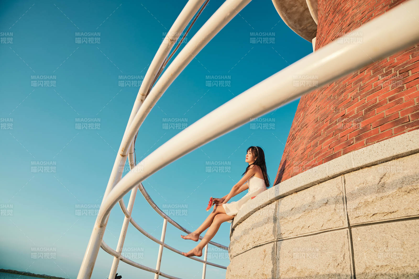 盛夏夕阳湖边码头灯塔上吃西瓜的少女