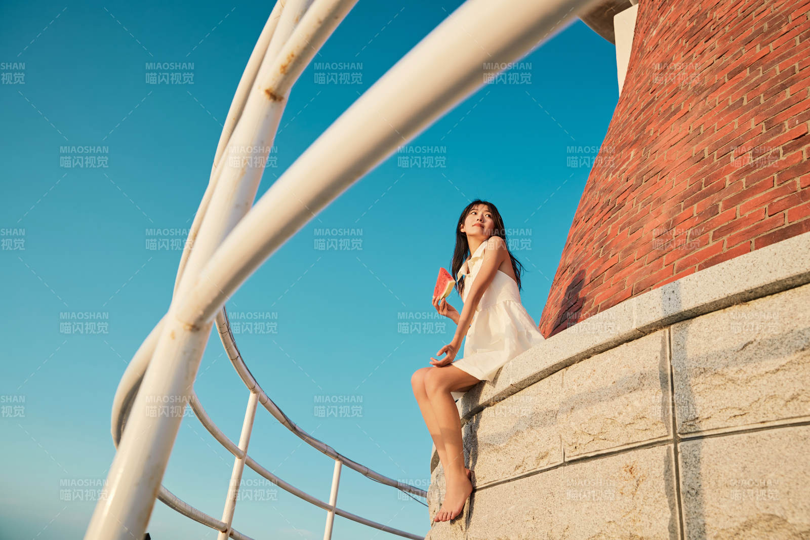 盛夏夕陽湖邊碼頭燈塔上吃西瓜的少女